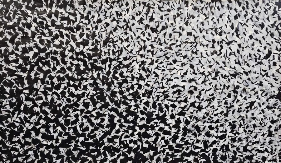 Thousands of small black marks speckled across white paper, collecting into a dark band along the lower edge.