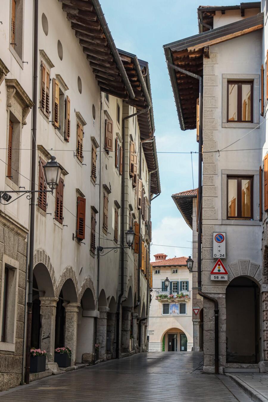 A narrow street of tall houses with an arcaded walkway running along the ground floor.