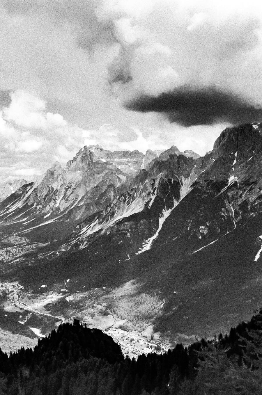 Black and white photograph of a long mountain range with a dark lens of cloud hanging over the summit.