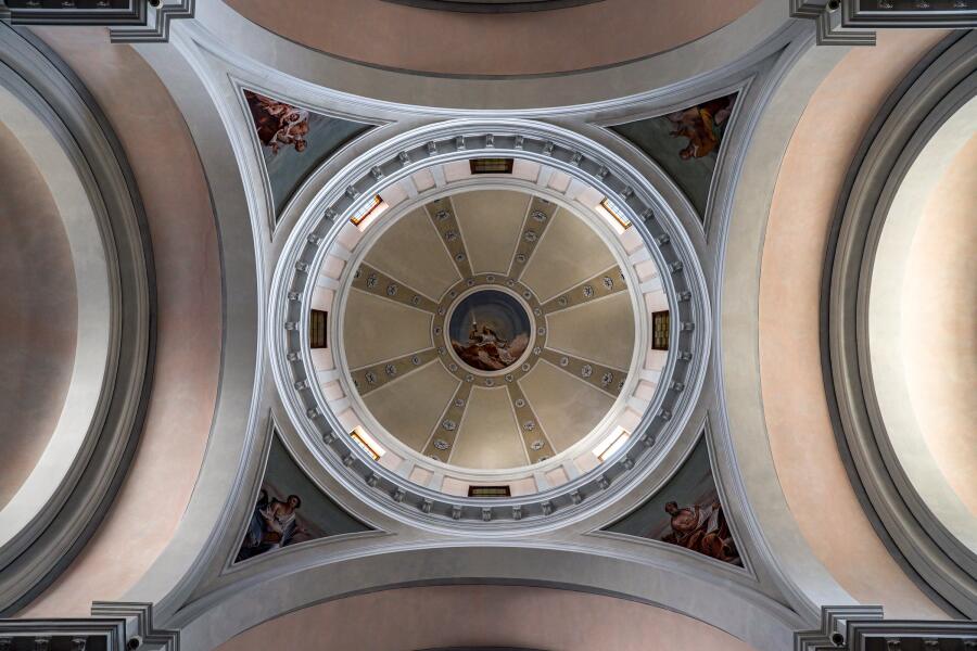 A church dome photographed straight up from the crossing, ringed with windows and pale painted vaults.
