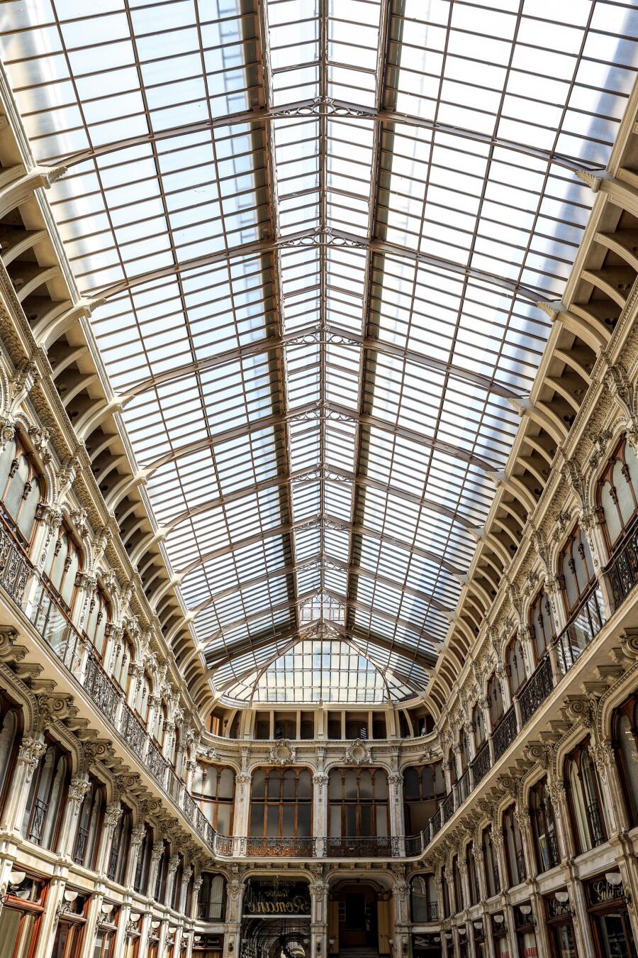The glazed barrel roof of a shopping arcade seen from below, its steel ribs converging into the distance.