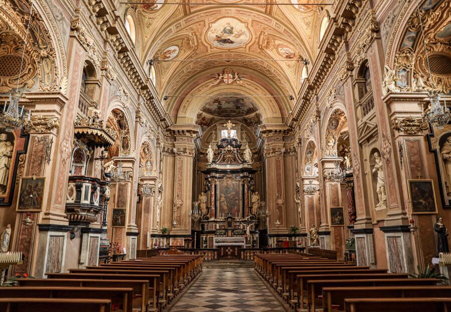 Interior of a baroque church looking down the nave toward a gilded high altar, with painted ceilings and carved side chapels.