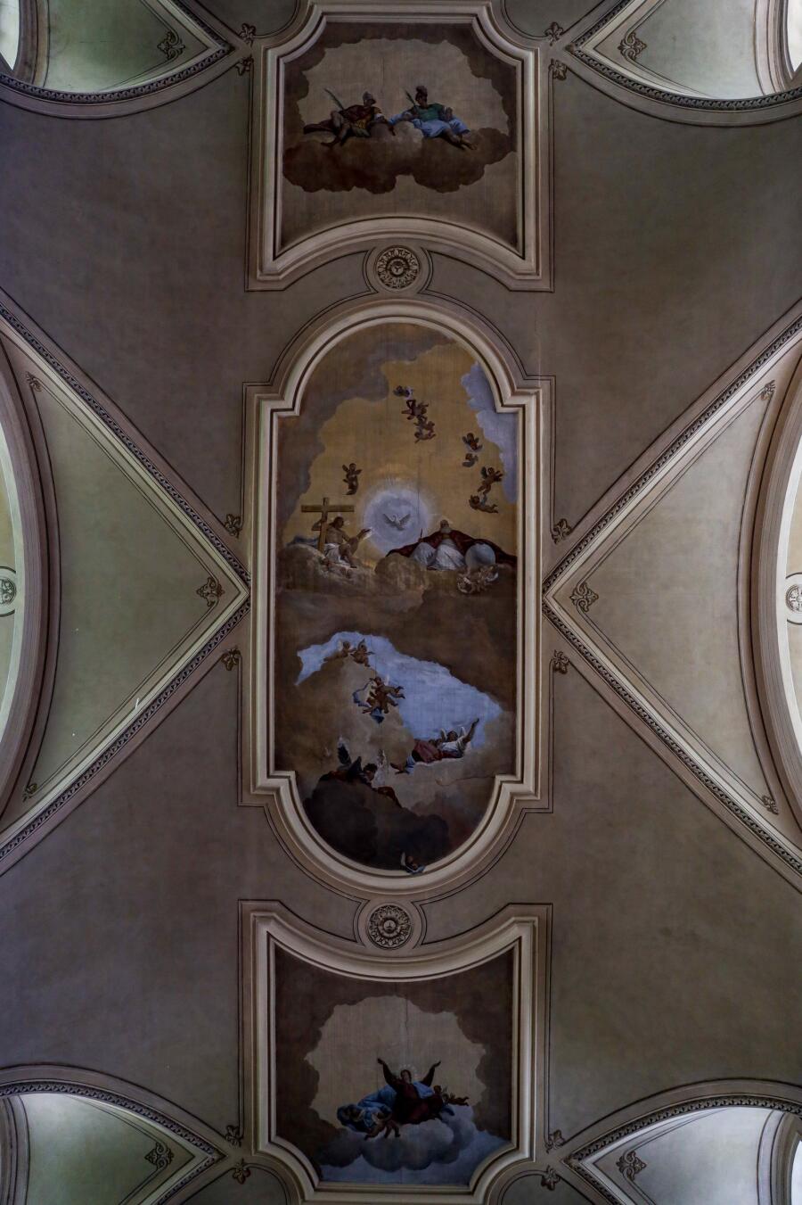 A church ceiling vault seen from directly below, with painted figures set into pale ribbed panels.