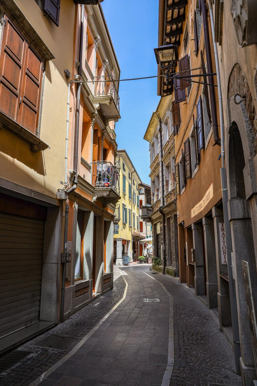 A steep narrow street lined with balconied houses in ochre and cream, empty in the middle of the day.