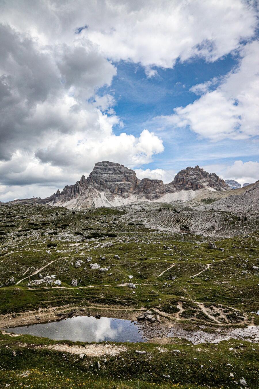 A shallow pool on a high stony plateau reflecting the sky, with rock towers on the horizon.